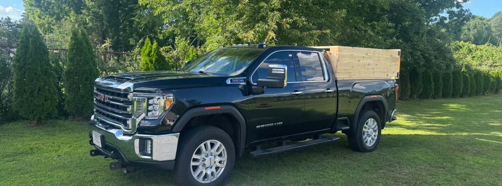 Colonial Cleanouts black GMC 2500HD pickup with chrome grille, tow mirrors, and wooden bed sides